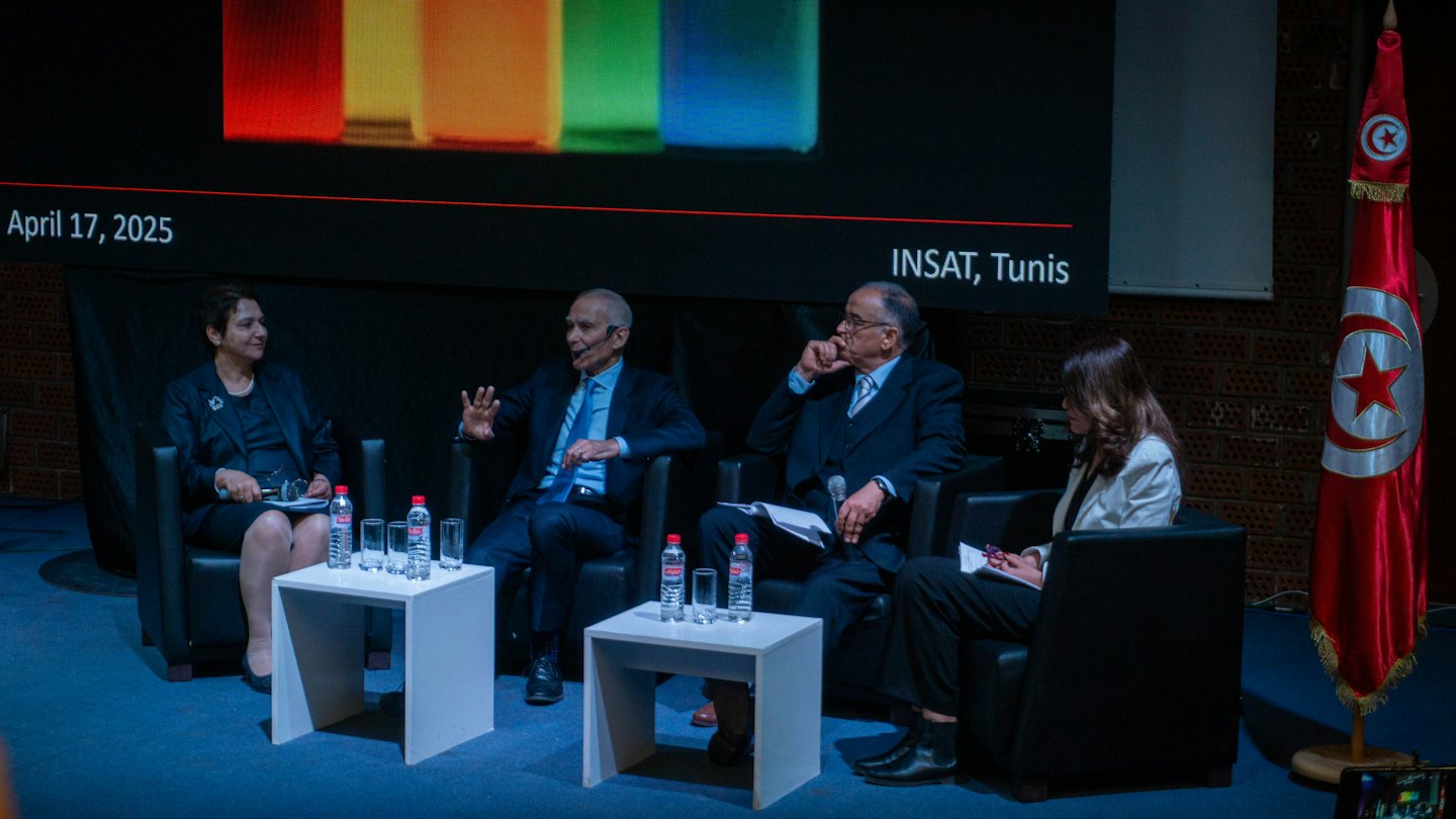 Four professionals sit on a panel discussing topics on stage.